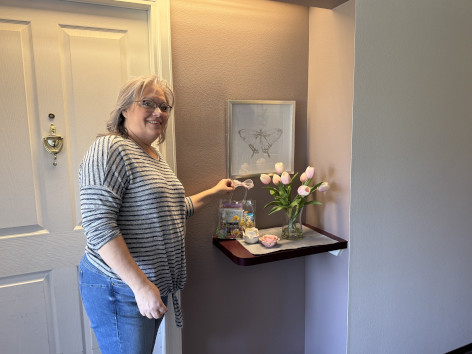 A SANEWA volunteer placing flowers and a May Day basket at a resident's apartment door