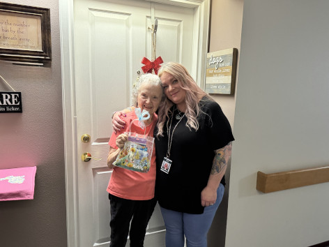 A Cherrywood Place resident receiving a May Day basket from a community caregiver