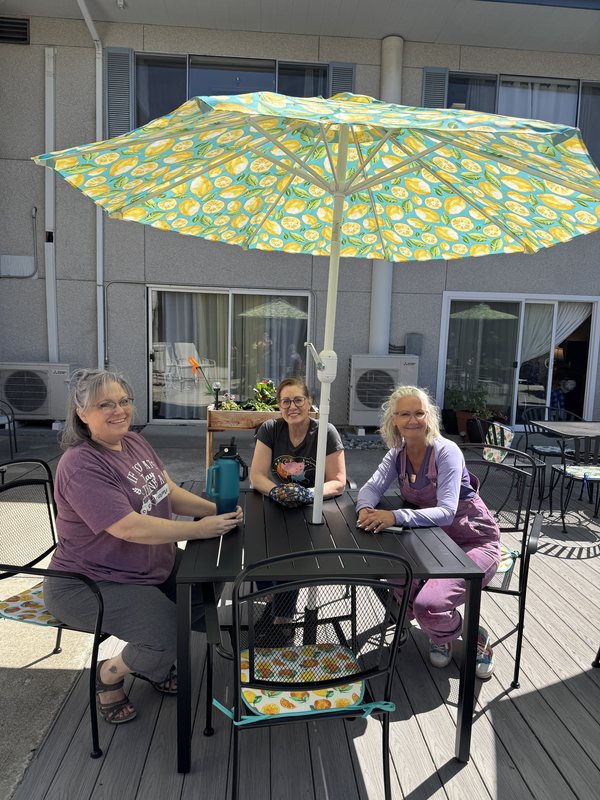 Three volunteers seated at the refreshed Wedgewood patio table